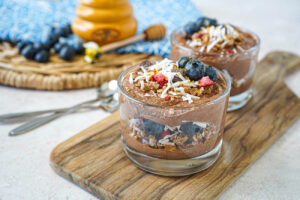 Chocolate Ricotta Parfait in two glasses with honey and bluberries in the background.
