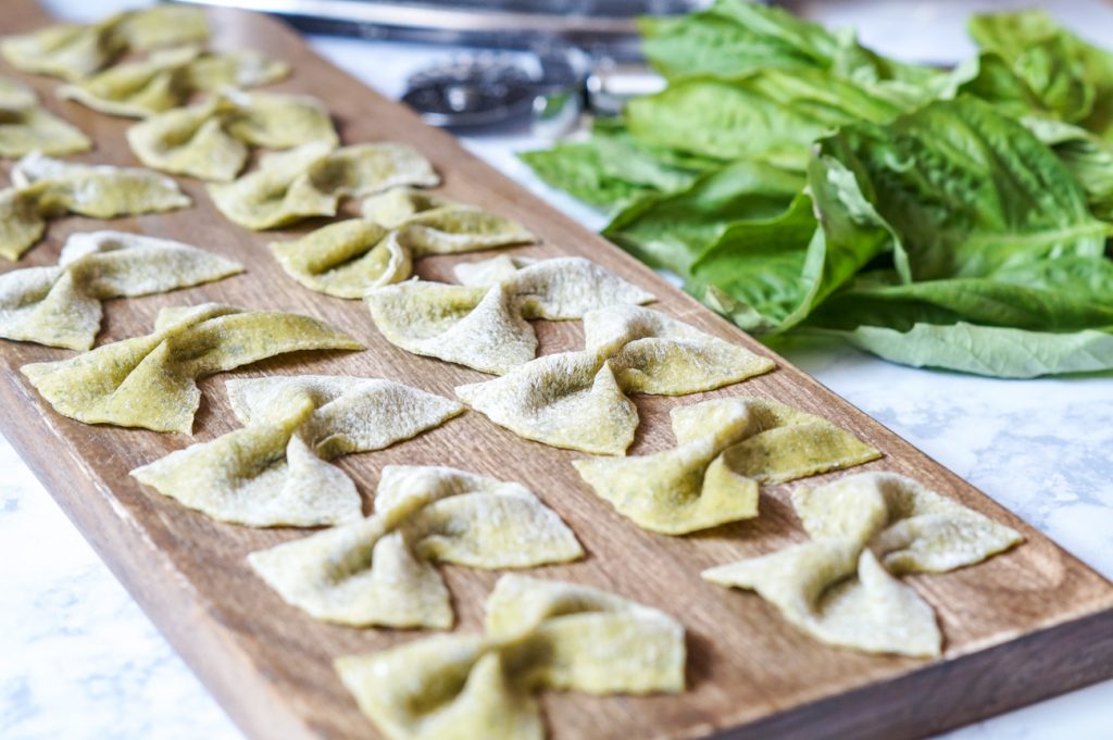Side view of Homemade Basil Farfalle arranged in a single layer on a wooden board.
