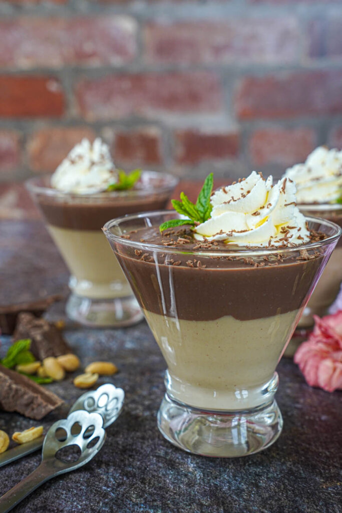 Side view of Chocolate and Peanut Butter Pudding in a glass with whipped cream and a mint sprig.