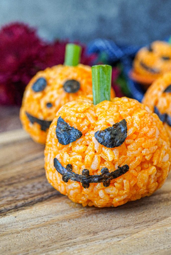 Close up of Jack-O-Lantern Carrot Rice with nori face and green onion stem.