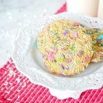 Three Sprinkle Sugar Cookies on a small white pedestal.