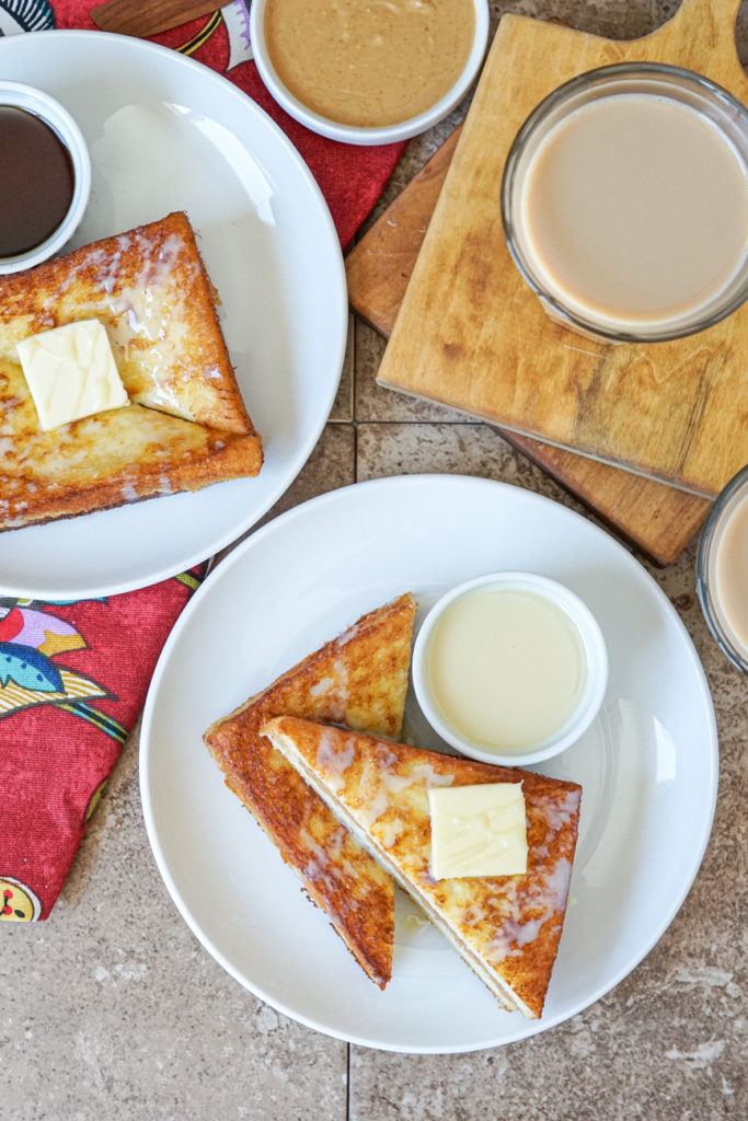 Aerial view of Hong Kong Style French Toast on two white plates alongside two glasses of milk tea.