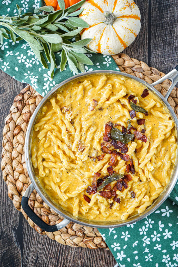 Aerial view of Pumpkin and Cider Macaroni and Cheese in a pan topped with bacon and sage.