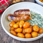 Brunede Kartofler (Danish Browned Potatoes) on a plate with sausage and creamed kale.