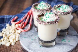 White Chocolate Peppermint Mousse in three clear glasses next to candy canes.