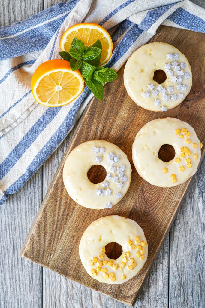Aerial view of four Meyer Lemon Doughnuts on a wooden board.