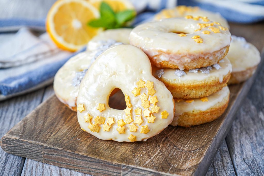 A stack of round and heart-shaped Meyer Lemon Doughnuts topped with star sprinkles.