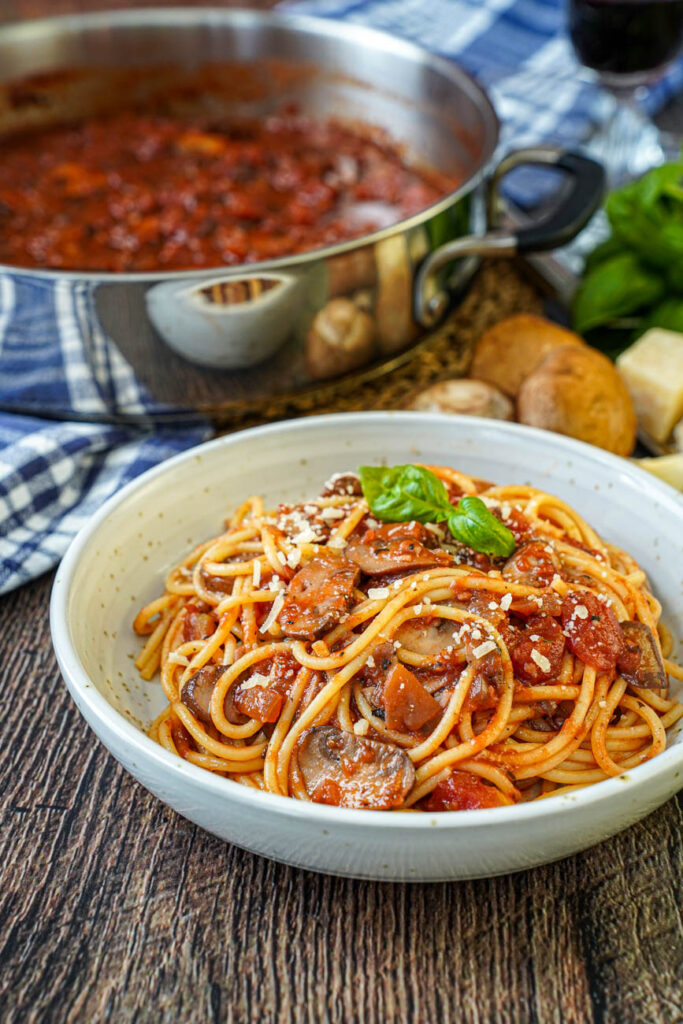Mushroom Tomato Sauce in a bowl with spaghetti and more in the background in a pan.