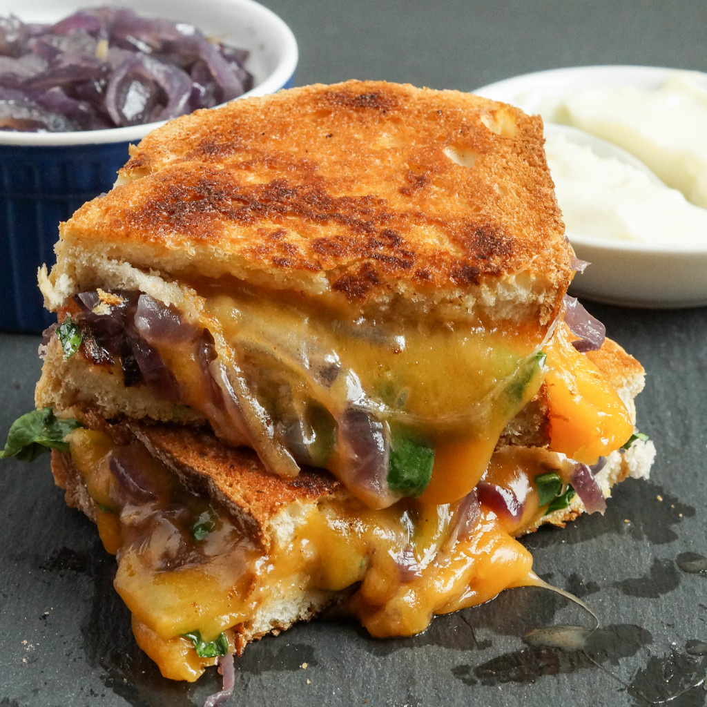 Two stacked slices of Grilled Cheese with Caramelized Onions and Spinach.
