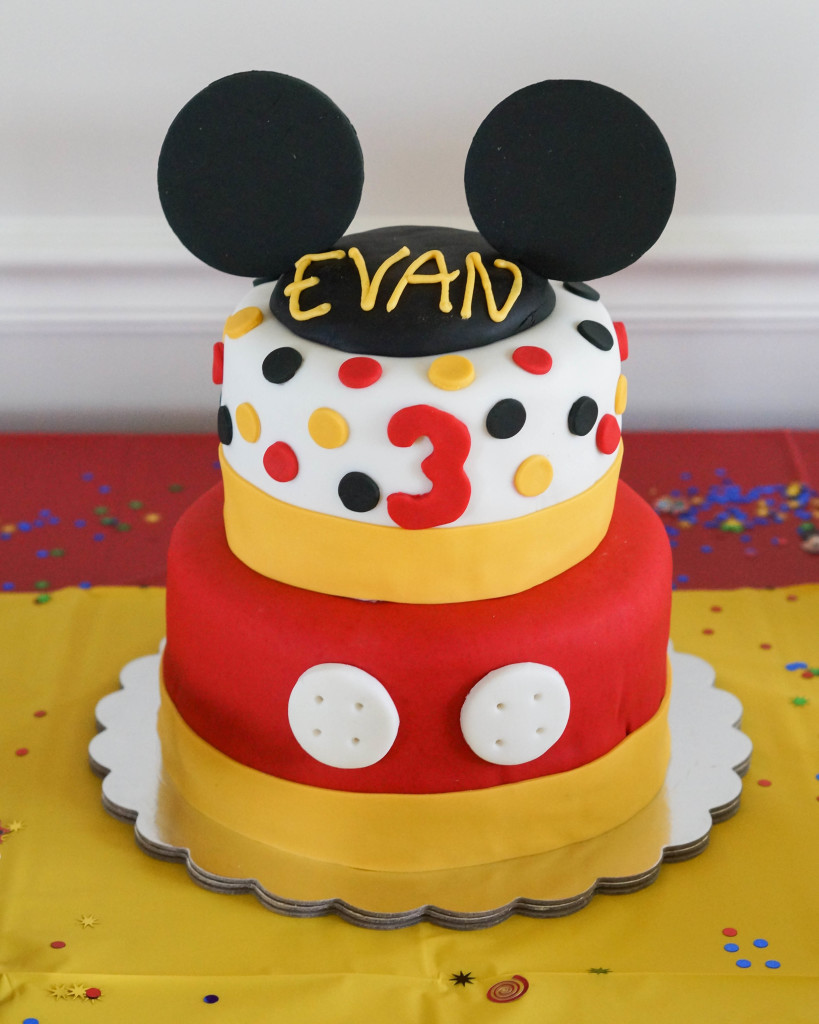 Mickey Mouse Birthday Cake with two tiers and black ears on top.