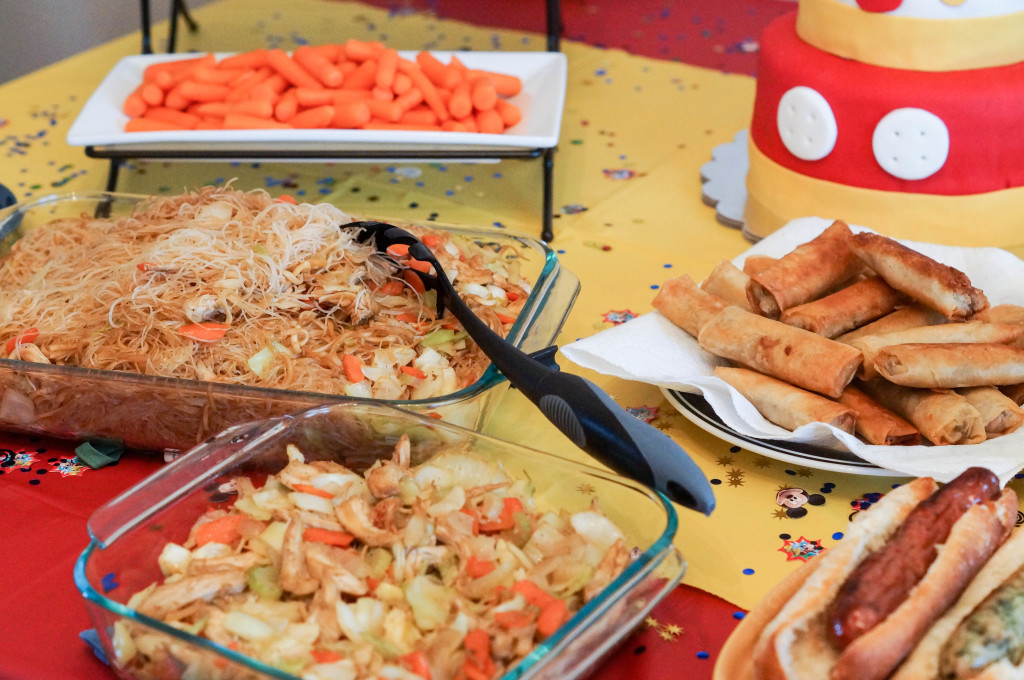 Lumpia, Hot Dogs, Pancit, and Carrots on a table.