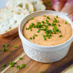 Liptauer (Austrian Cheese Spread) in a cream-colored ramekin next to baguette slices and speck.