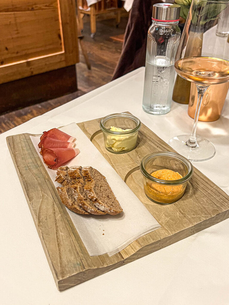 Board with Liptauer (Austrian Cheese Spread), butter, speck, and baguette slices.