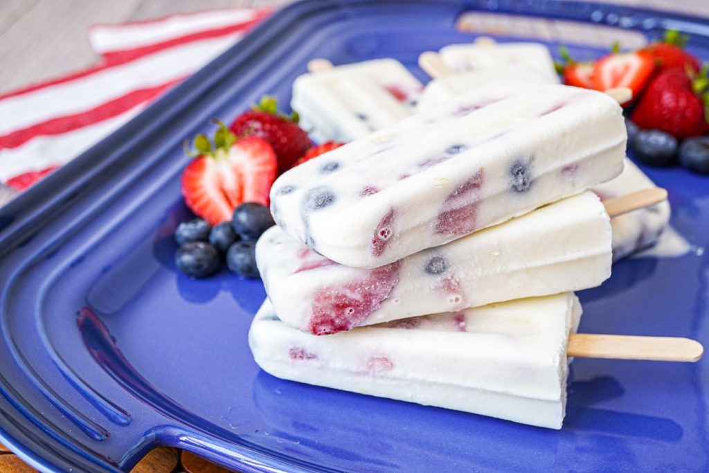 A stack of three Berry Yogurt Popsicles on a blue platter.