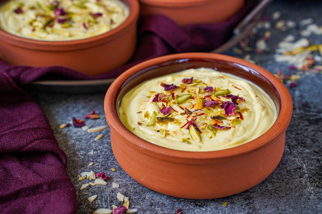 Kesar Elaichi Shrikhand (Indian Sweetened Saffron Cardamom Yogurt) in two clay bowls.