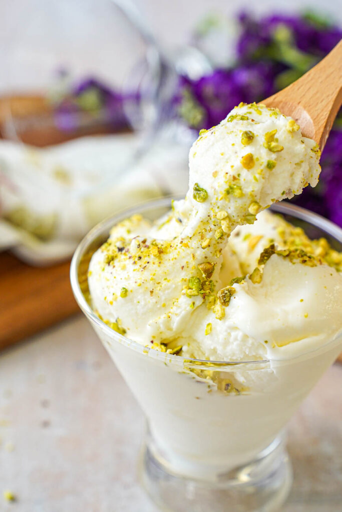 A wooden spoon pulling up Mastic Ice Cream from a bowl.