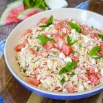 Watermelon Feta Orzo Salad in a large blue bowl on a round wooden board.