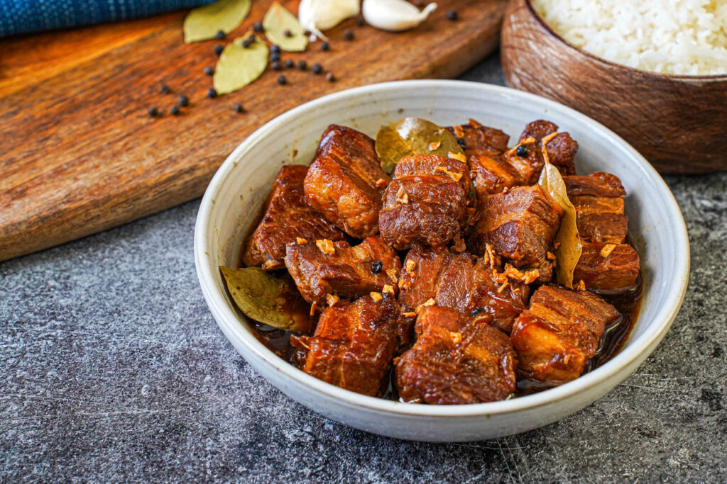 Adobong Baboy (Filipino Pork Adobo) in a bowl next to a bowl of rice.