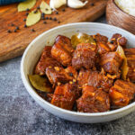 Adobong Baboy (Filipino Pork Adobo) in a bowl next to a bowl of rice.