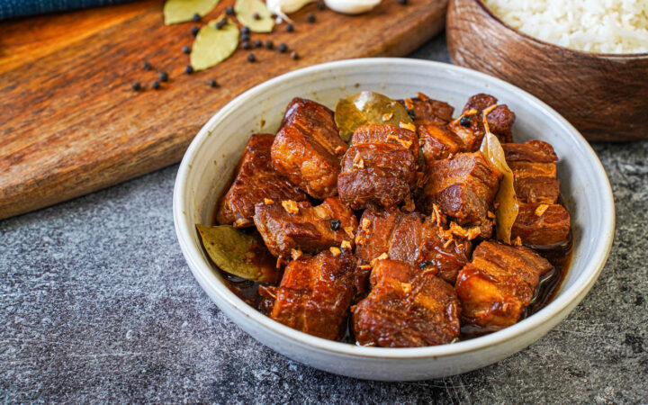 Adobong Baboy (Filipino Pork Adobo) in a bowl next to a bowl of rice.