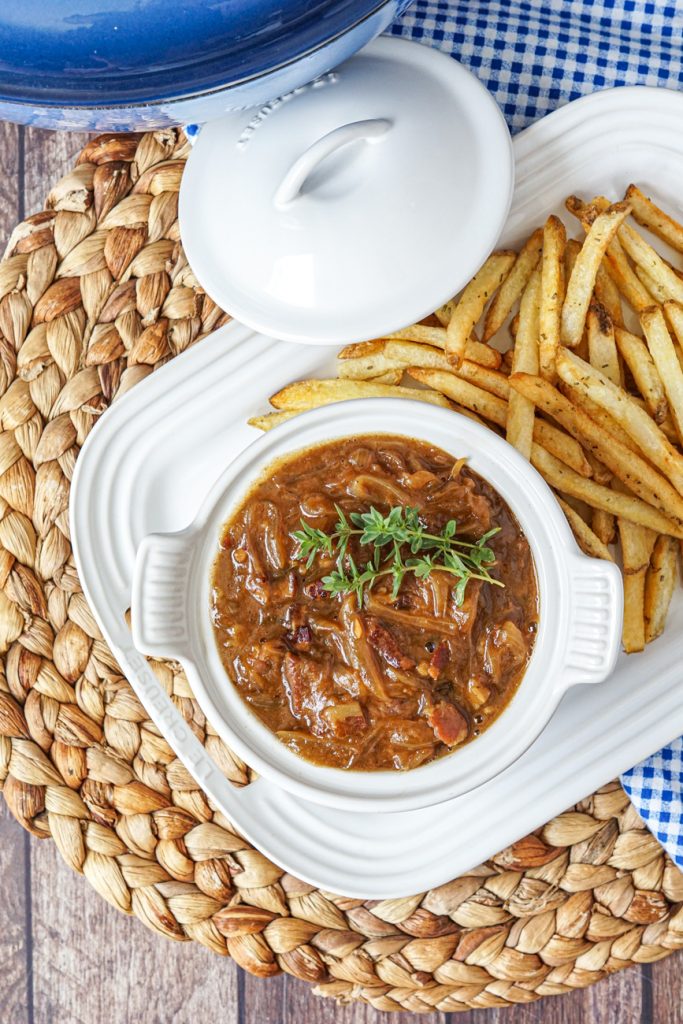 Aerial view of Carbonnade Flamande (Flemish Beef and Beer Stew) in a white bowl next to fries.
