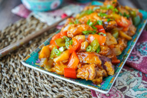 Gulou Yuk (Cantonese Sweet and Sour Pork) on a rectangular plate next to brown chopsticks.