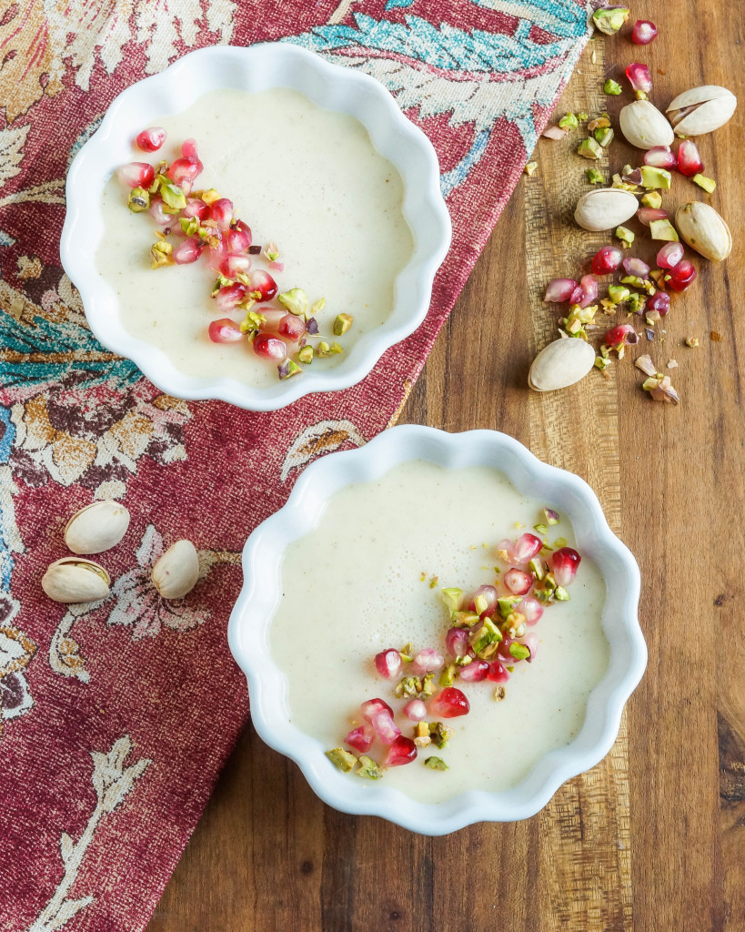 Aerial view of Mishti Dohi (Indian Baked Sweet Yogurt Cream) in two white ramekins with pistachios and pomegranate seeds.