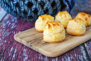Five Túrós Pogácsa (Hungarian Quark Pogácsa) on a wooden board.