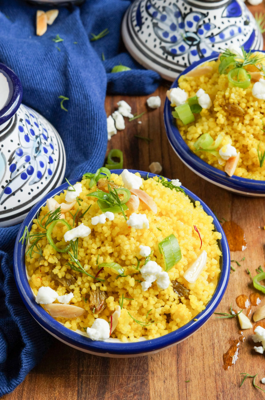 Close up of Yellow Couscous in two miniature clay blue/white tagines next to a blue towel.