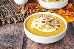 Creamy Sweet Potato Soup topped with pecans in a white bowl.