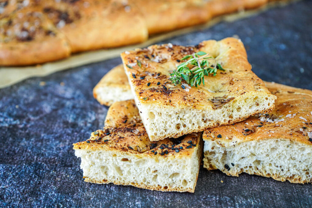 A stack of Eastern-Style Focaccia slices topped with thyme sprigs.