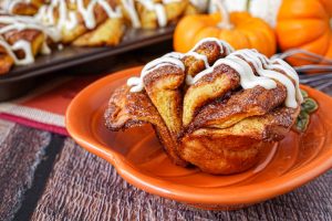 Pumpkin Cinnamon Fantail Roll on a pumpkin plate with pumpkins in the background.