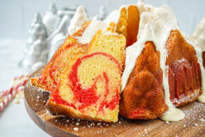 Peppermint Bundt Cake on a wooden board with two slices cut out to show red marbling.