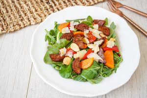 Chorizo and Sweet Potato Salad on a white plate next to two copper forks.