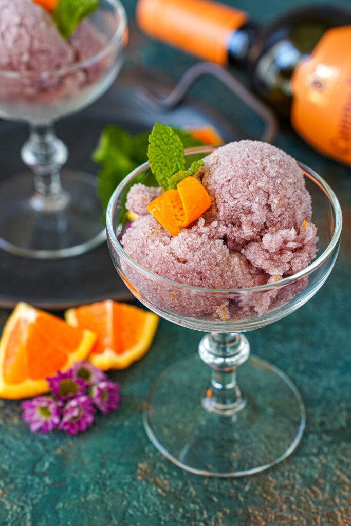 Sorbete de Vino Tinto (Red Wine Sorbet) in two glasses with an orange wine bottle in the background.