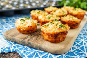 Nine Three Cheese Macaroni Bites on a wooden board.