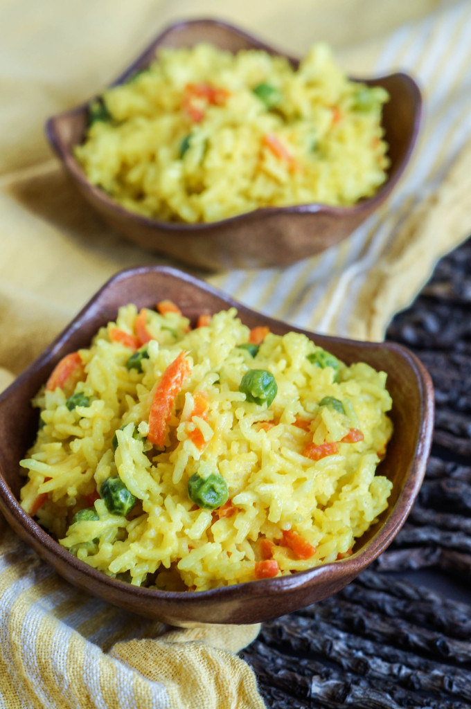 Side view of Wali Wa Junde Na Karoit (Tanzanian Coconut Rice with Peas and Carrots) in two brown bowls.
