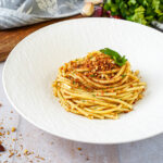 Pasta con la Mollica (Pasta with Breadcrumbs) in a large white bowl with parsley sprigs.