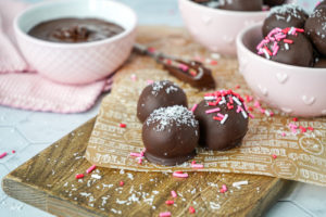 Three Salted Dark Chocolate Coconut Balls on parchment with more in pink bowls.