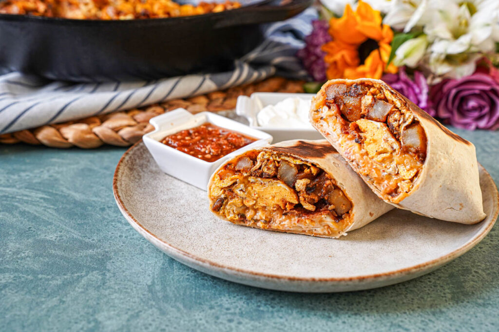 Bacon Breakfast Burritos on a plate with small bowls of salsa and sour cream.