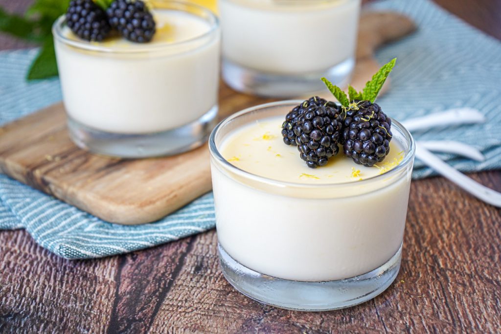 Lemon Posset in three glass cups with blackberries and mint.