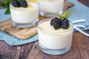 Lemon Posset in three glass cups with blackberries and mint.