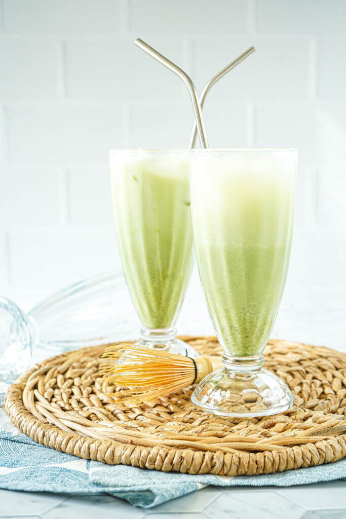Side view of Matcha Egg Cream in two tall glasses with metal straws.