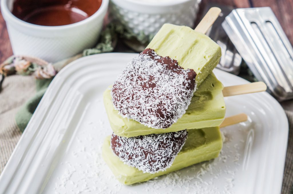 A stack of four Paletas de Aguacate y Coco (Mexican Avocado and Coconut Popsicles) on a white platter.