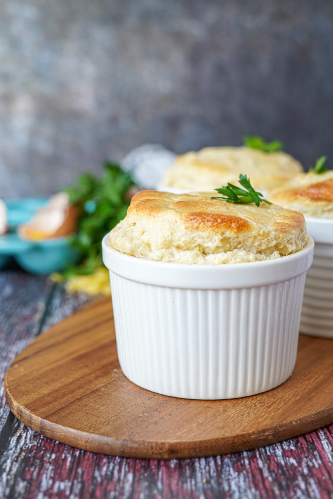 Side view of Macaroni and Cheese Soufflé in a white ramekin and topped with a parsley leaf.