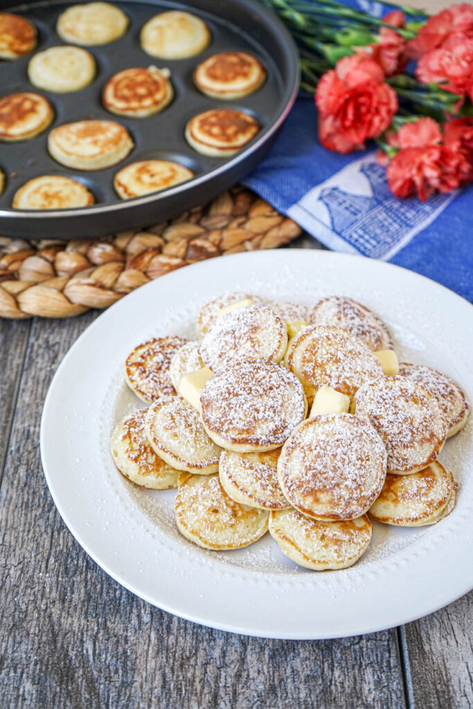 Poffertjes (Dutch Mini Pancakes) topped with butter and powdered sugar.