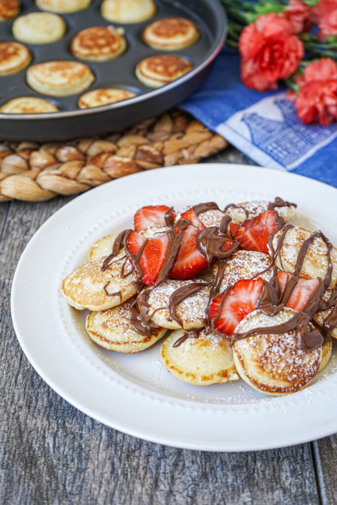 Poffertjes (Dutch Mini Pancakes) topped with fresh strawberries and Nutella.