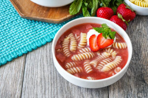 Zupa Truskawkowa (Polish Strawberry Soup) in a white bowl with noodles, strawberry slices, and mint.