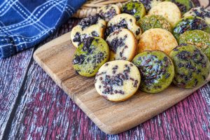 Kue Cubit (Indonesian Pinch Cake) on a wooden board with sprinkles, Oreos, and coconut.
