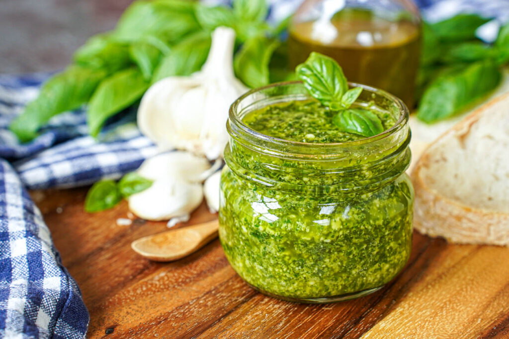 Pistou (Provençal Basil Sauce) in a jar with a sprig of basil on top.